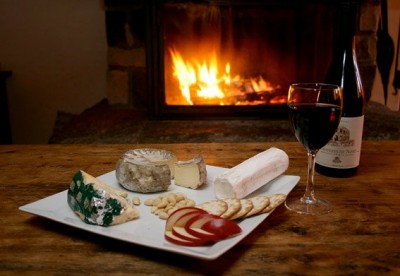 Cheese board with a glass of wine by the fireplace