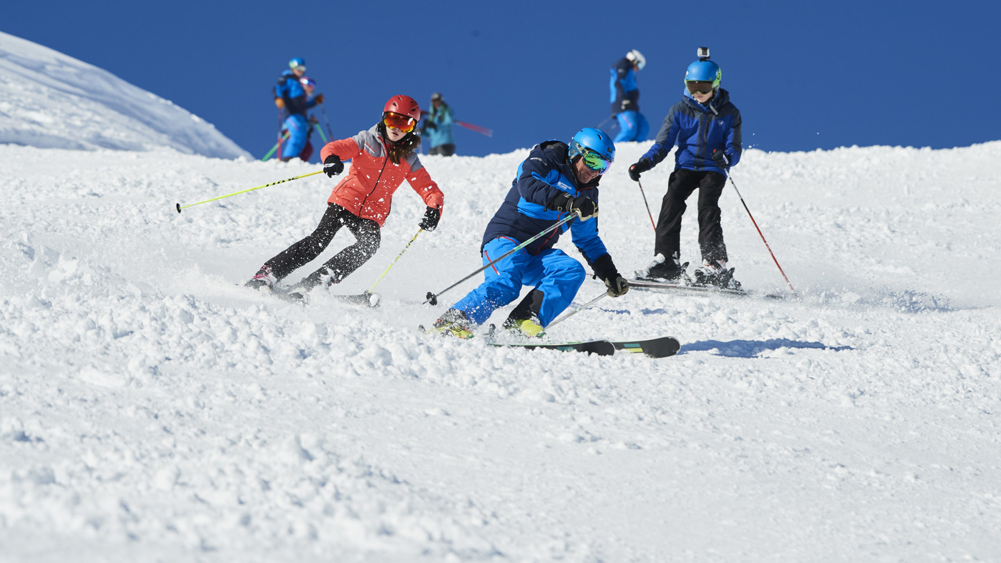 Older children on the ski slopes with instructor.