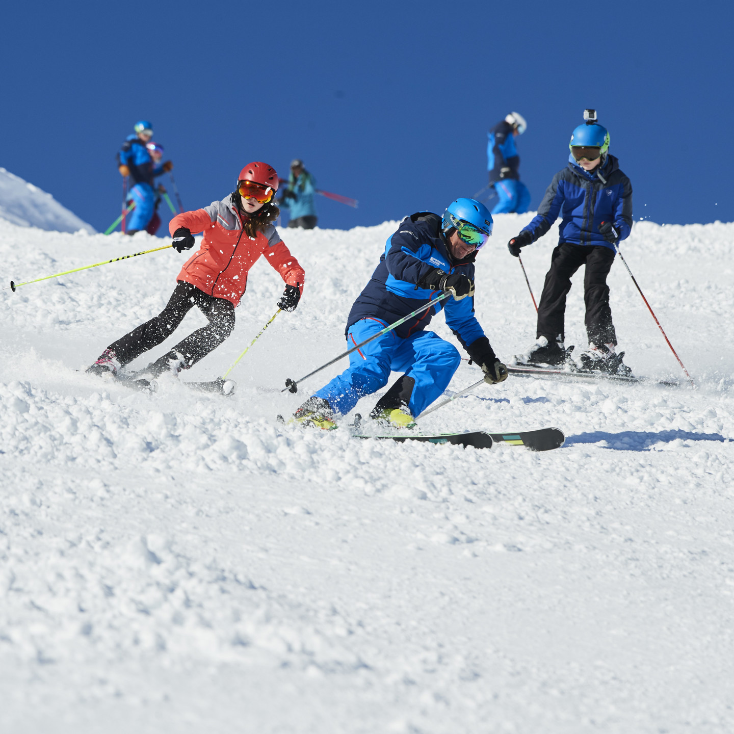 Older children on the ski slopes with instructor.